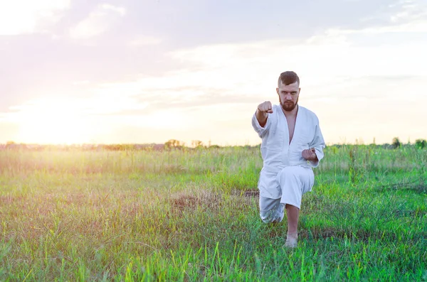 Kampsporten karate, en man i en kimono tränar utomhus, — Stockfoto