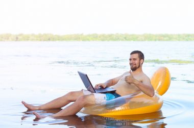 Şişme wate ringde otururken dizüstü bilgisayar üzerinde çalışan iş adamı