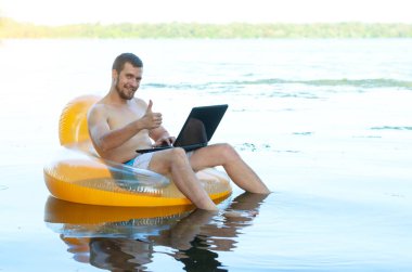 Şişme wate ringde otururken dizüstü bilgisayar üzerinde çalışan iş adamı