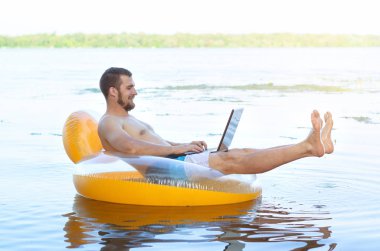 Şişme bir ringde oturan bir dizüstü bilgisayar üzerinde çalışan iş adamı