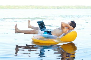 Şişme bir ringde oturan bir dizüstü bilgisayar üzerinde çalışan iş adamı