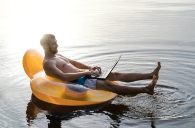 Bir dizüstü bilgisayarda wat şişme bir halka üzerinde işadamı