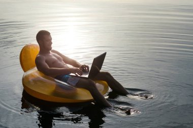 Adam bir kauçuk halka günbatımı, ücretsiz sp, su üstünde laptop ile