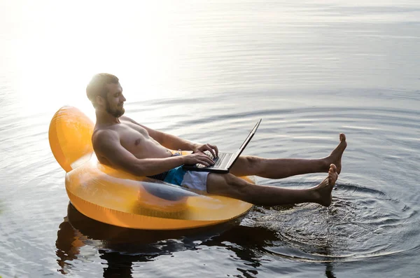 Bir dizüstü bilgisayarda wat şişme bir halka üzerinde işadamı