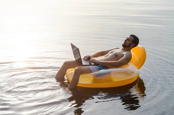 Adam bir kauçuk halka günbatımı, boş alan, su üstünde laptop ile