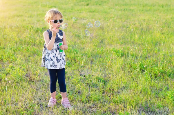 Kleines Mädchen pustet Blasen im Freien, freier Raum. — Stockfoto