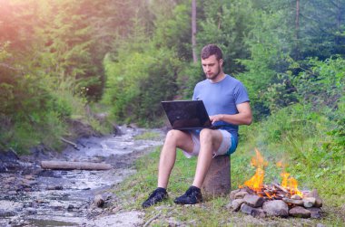Dizüstü bilgisayar açık havada ile oturan genç adam boş alan.