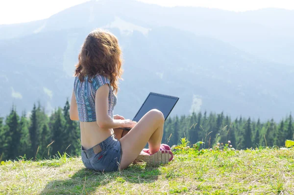 Slender woman with a laptop on top of a mountain, free space.