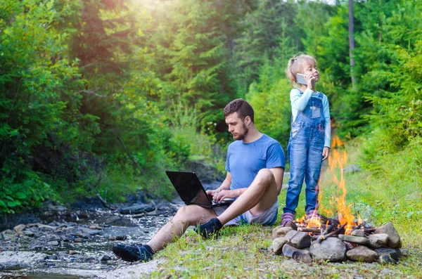 Papa avec ordinateur portable et fille avec mobile sur la nature, espace libre — Photo