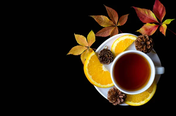 Hojas de otoño y una taza de té se aíslan en un fondo negro — Foto de Stock