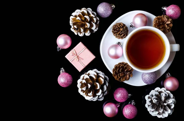 Bolas de Navidad y una taza de té caliente aislado en un backgro negro — Foto de Stock
