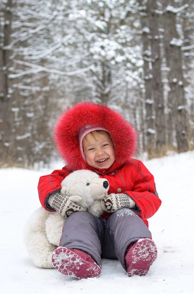Happy child with teddy bear in the snow.
