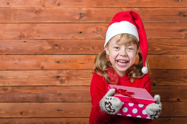 Happy child with a gift on a wooden background with copy space. — Stock Photo, Image