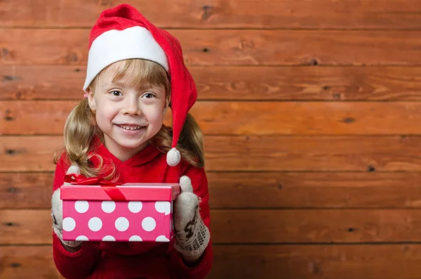 Happy child with a gift on a wooden background with copy space. — Stock Photo, Image