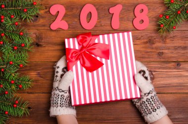 Bir çocuk bir Noel hediyesi ahşap bir masa üzerinde tutuyor.