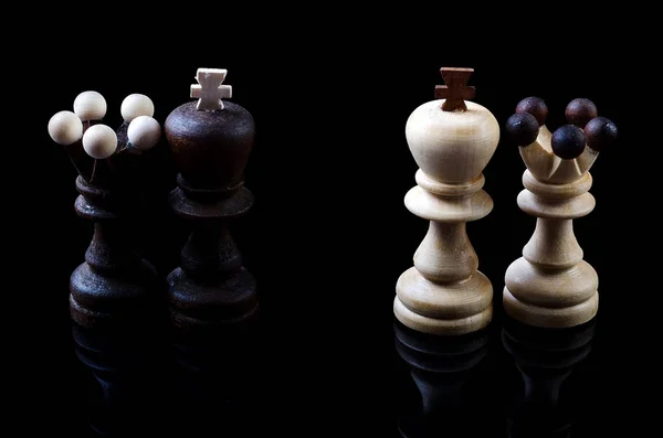 Chess pieces of the king and queen are isolated on black.