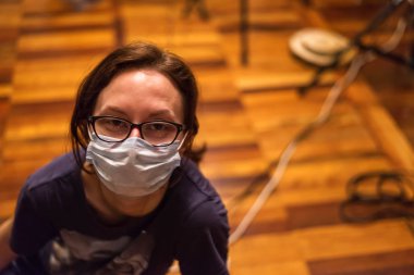 Kadının yüzü maske korumalı öksürüğü var.