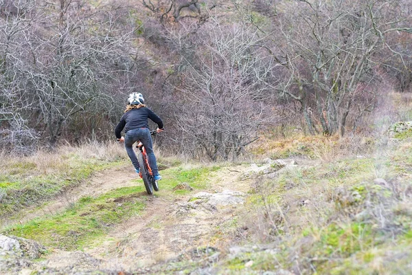 Profi kerékpáros, egy mountain bike túrák, mentén a sziklás terep, hátsó nézet. — Stock Fotó