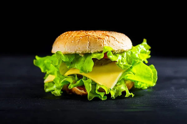 Burger proaspăt gustos pe fundal negru . — Fotografie, imagine de stoc