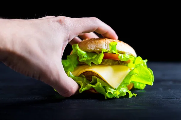 Hamburguesa fresca y apetitosa sobre una mesa negra de madera, pancarta publicitaria . — Foto de Stock