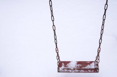 Kışın kar yağarken boş salıncak.