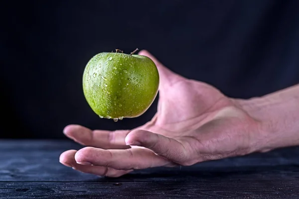 Levitation fresh green apple on a wooden table.