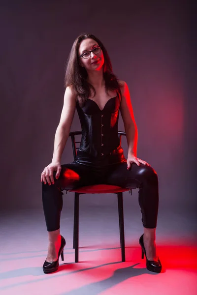 Sexy jonge vrouw in een korset en de latex op een stoel. — Stockfoto