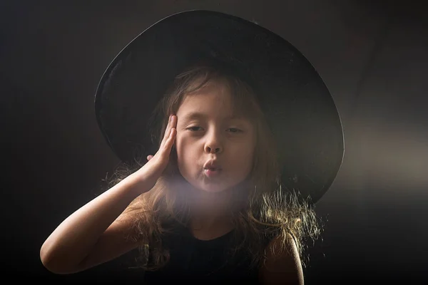 Kislány a sötét háttér előtt, banner Halloween boszorkány kalap. — Stock Fotó