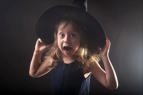 Karanlık bir arka plan afiş için halloween cadı şapkalı küçük kız. — Stok fotoğraf