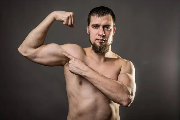 Bonito fisiculturista muscular em um fundo cinza . — Fotografia de Stock