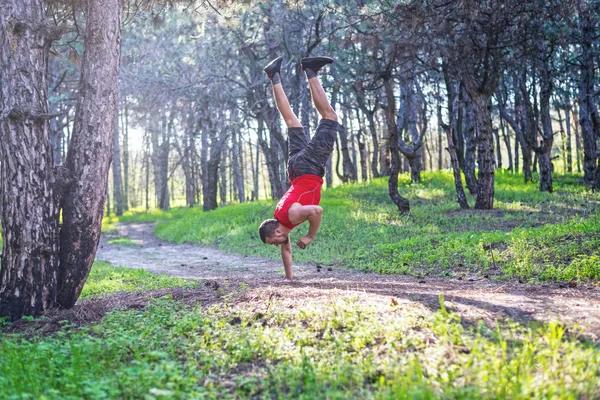 Hombre haciendo un puesto de mano en un sendero forestal, espacio libre . — Foto de Stock