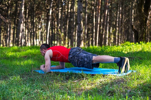 Man fitness trainer makes the bar outdoors.