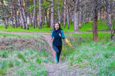 Genç kadın bahar ormanın içinden çalıştırmak bir sabahı.