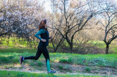 Genç kadın bahar ormanın içinden çalıştırmak bir sabahı.
