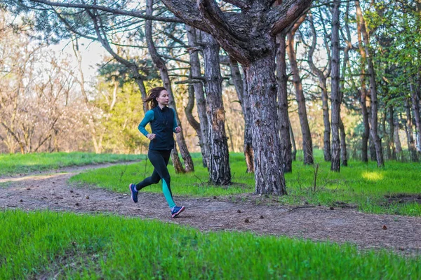 Mujer joven en una mañana correr a través del bosque de primavera . — Foto de Stock