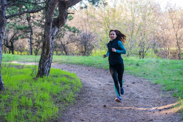 Junge Frau beim morgendlichen Lauf durch den Frühlingswald. — Stockfoto