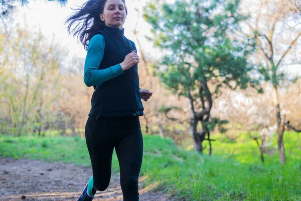 Mujer joven en una mañana correr a través del bosque de primavera . — Foto de Stock