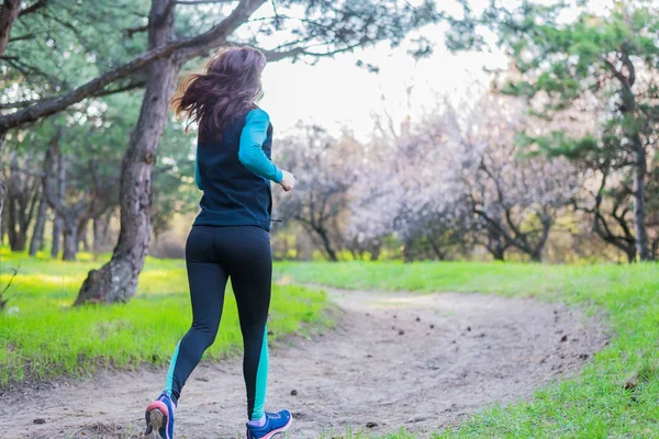 Mujer joven en una mañana correr a través del bosque de primavera . — Foto de Stock