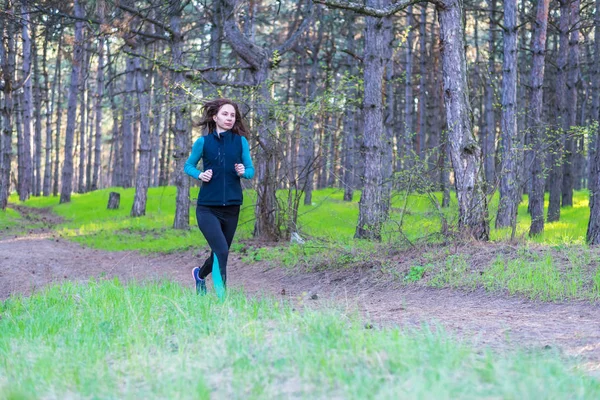 Mujer joven en una mañana correr a través del bosque de primavera . — Foto de Stock