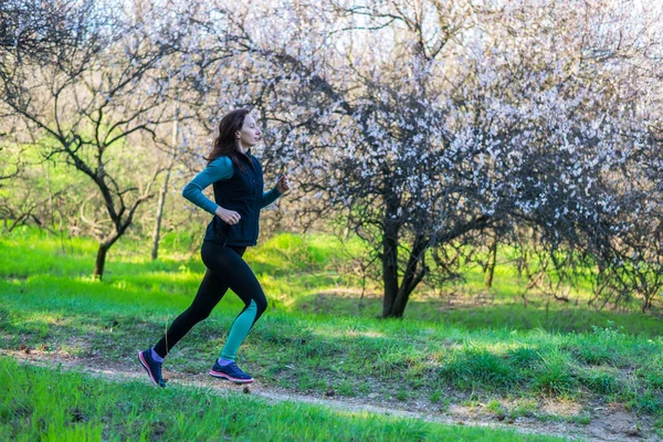 Mujer joven en una mañana correr a través del bosque de primavera . —  Fotos de Stock