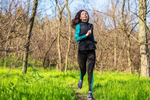 Mujer joven en una mañana correr a través del bosque de primavera . — Foto de Stock