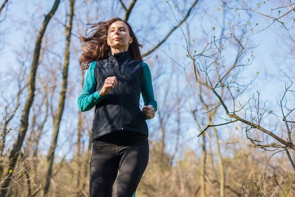 Mujer joven en una mañana correr a través del bosque de primavera . — Foto de Stock