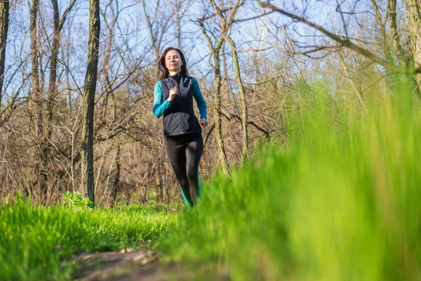 Genç kadın bahar ormanın içinden çalıştırmak bir sabahı.