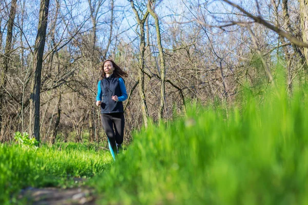 Mujer joven en una mañana correr a través del bosque de primavera . — Foto de Stock