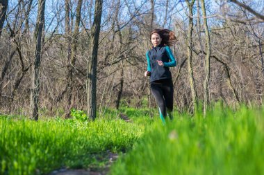 Genç kadın bahar ormanın içinden çalıştırmak bir sabahı.