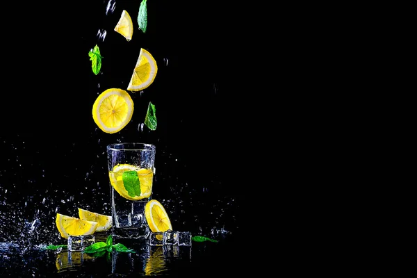 Lemonade with flying lemon and mint, isolated on a black background, free space.