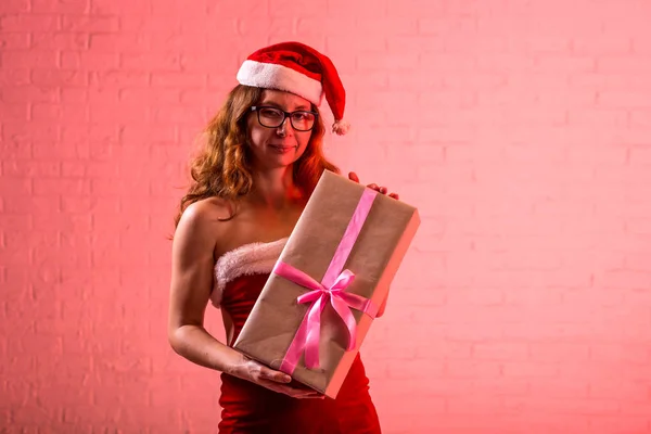 Buon Natale, ragazza con i cappelli di Babbo Natale e con in mano un regalo di Natale . — Foto Stock