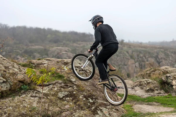 Ciclista en una bicicleta de montaña se eleva por el terreno rocoso . — Foto de Stock