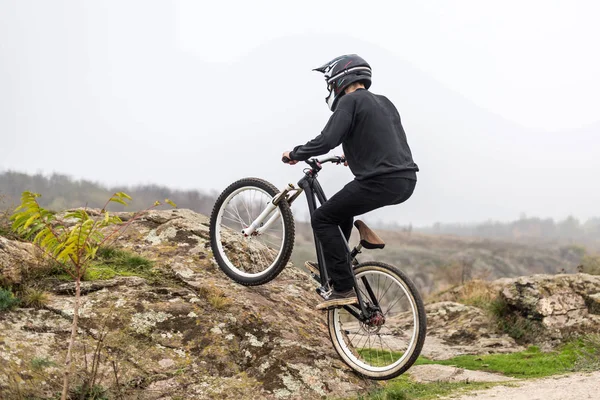 Ciclista en una bicicleta de montaña se eleva por el terreno rocoso . — Foto de Stock