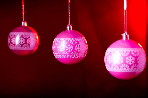 Παραδοσιακά ροζ μπάλες Χριστούγεννα σε μαύρο φόντο με κόκκινο πίσω φως. — Φωτογραφία Αρχείου
